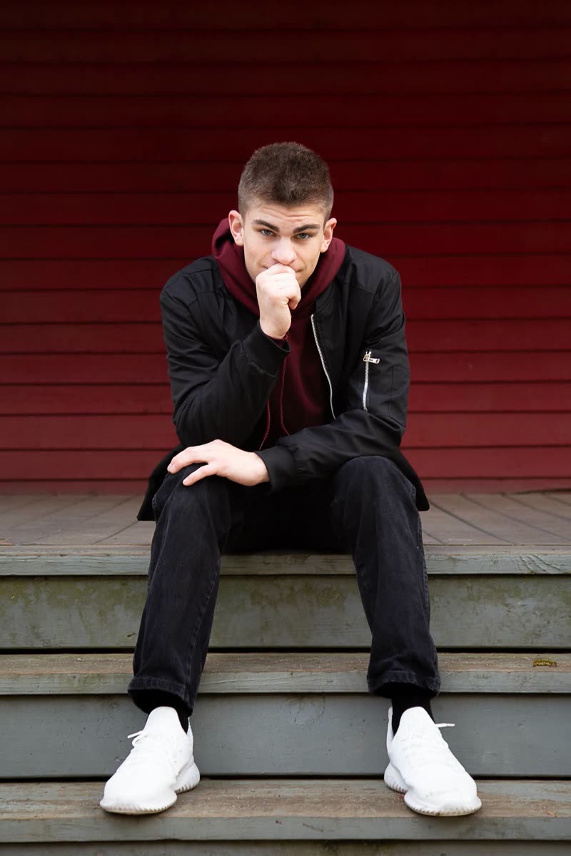 Preston Andersen seated on wooden steps in front of a red barn wall